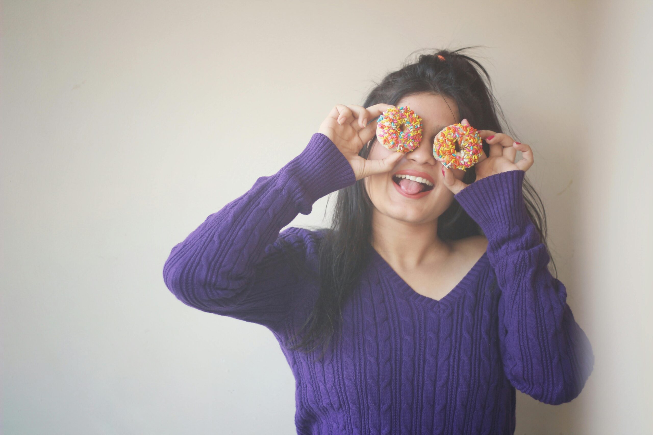 woman making a silly face with donuts before visiting our Union Square dentist